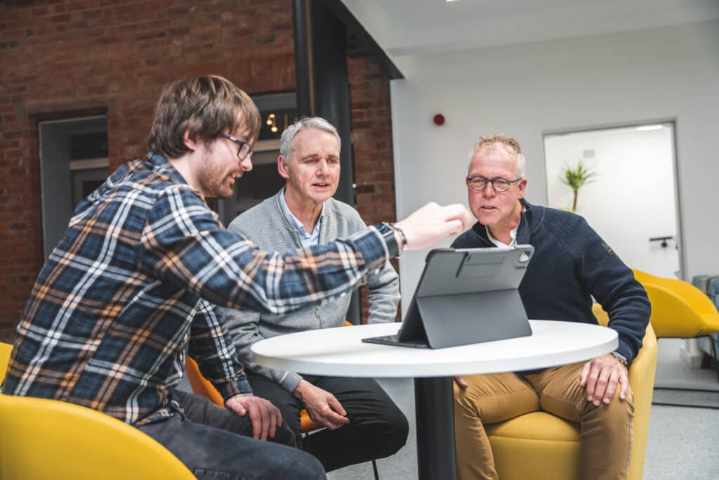 Clients talking to A Red Box team member about SEO while sat around a table looking at their website on a laptop