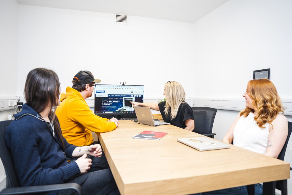 The Marketing Team and Web Designers are analysing a website for user expereince and customer journey / CRO sat around a table looking at a computer monitor