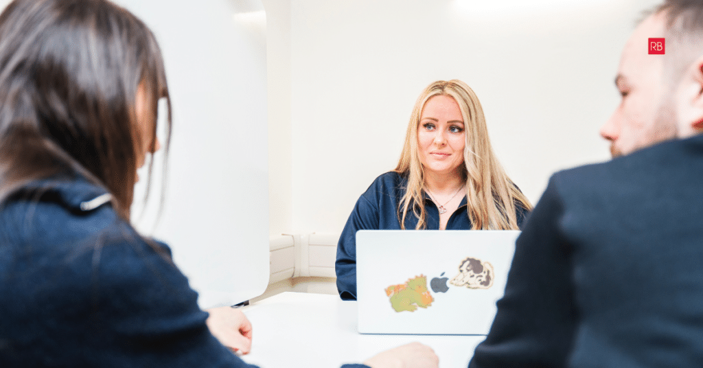Red Box team member leading a Industrial website design strategy meeting with two business professionals in a modern office