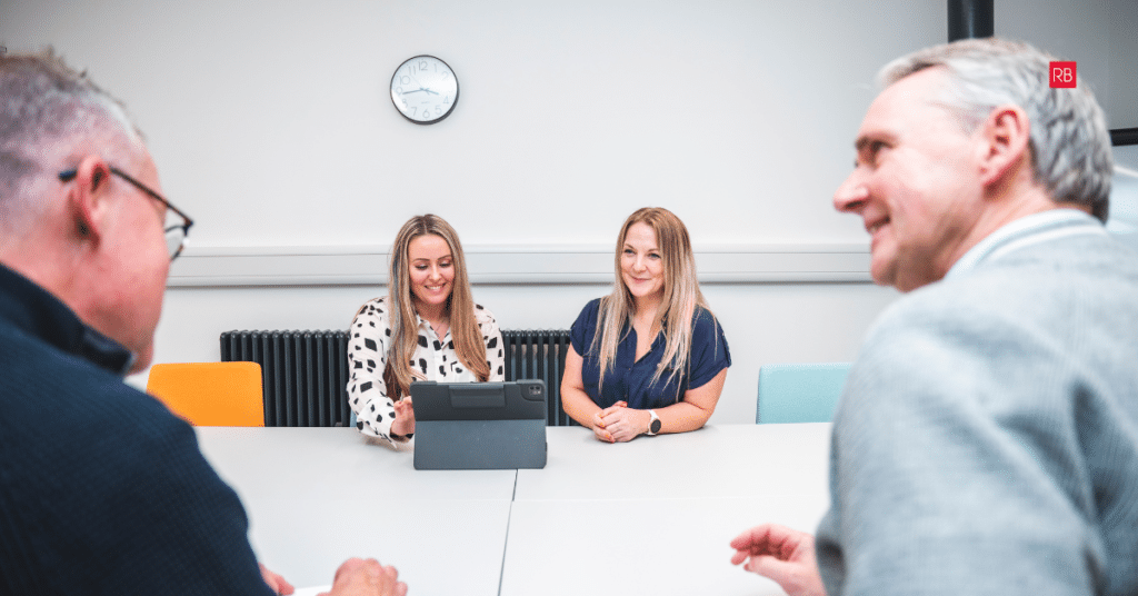 Business meeting with two clients and two team members reviewing a website on a tablet
